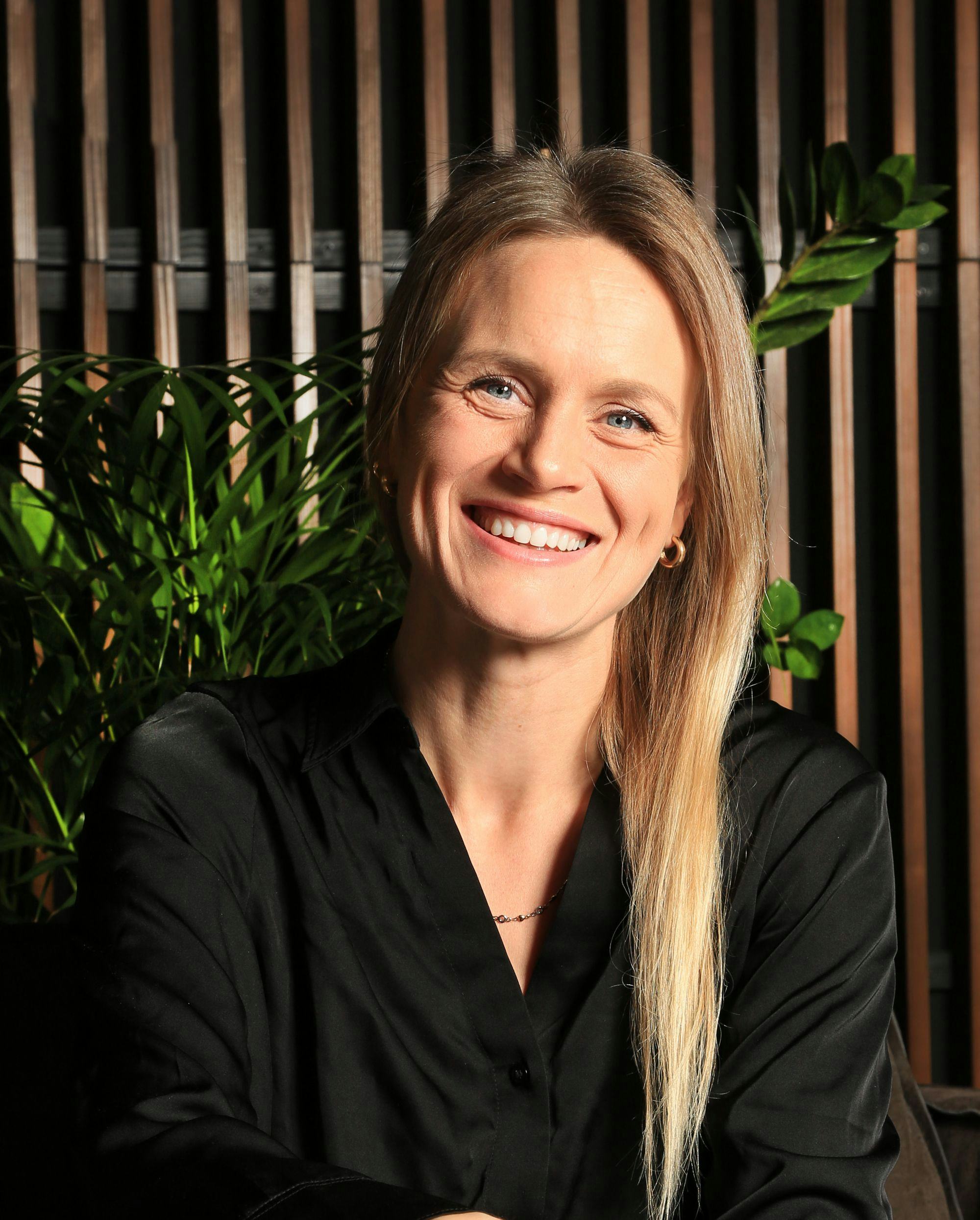 Portrait of a woman, green plants and wooden panel in background