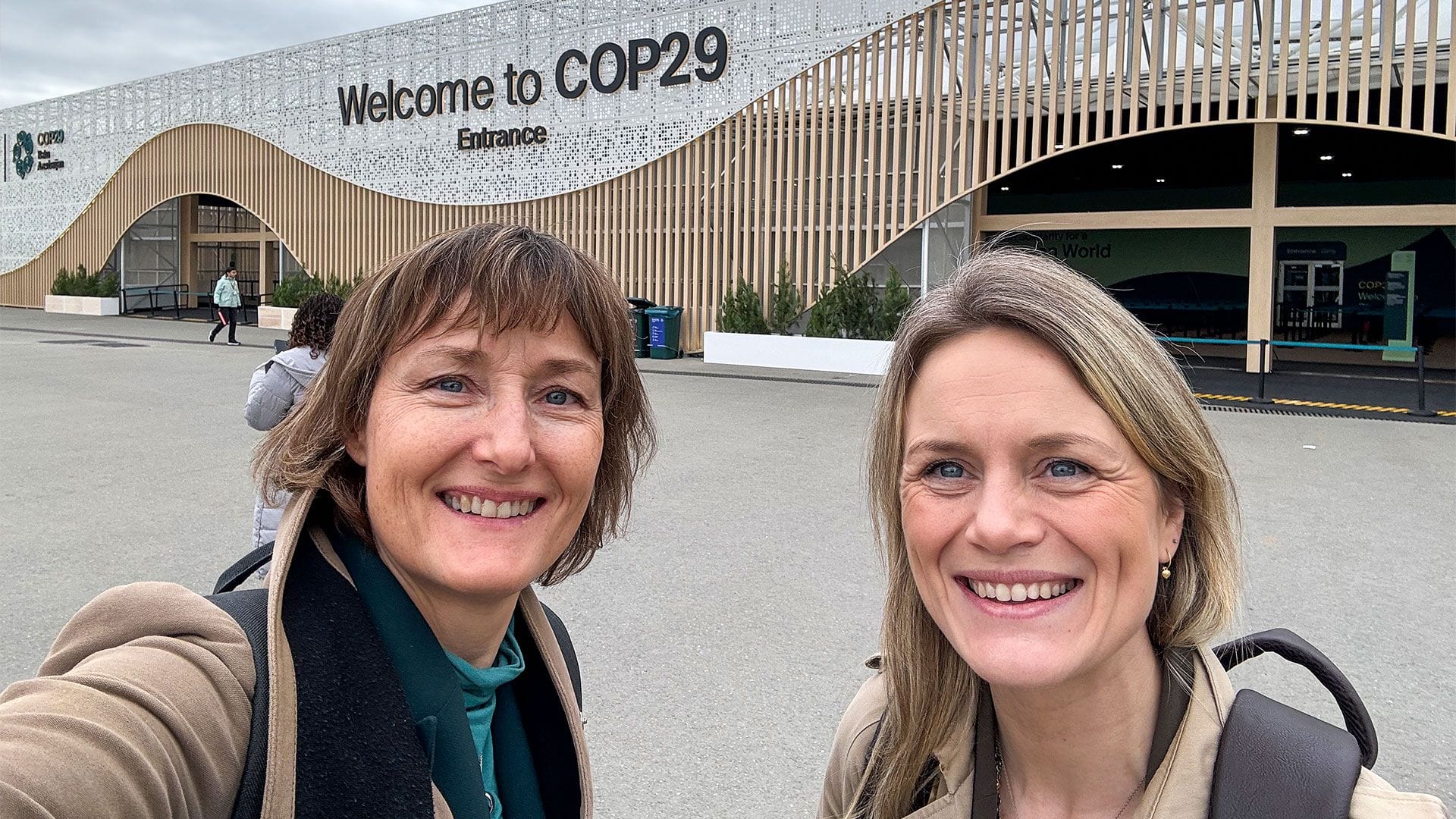 Two women in front the entrence at the 2024 COP29 in Baku.