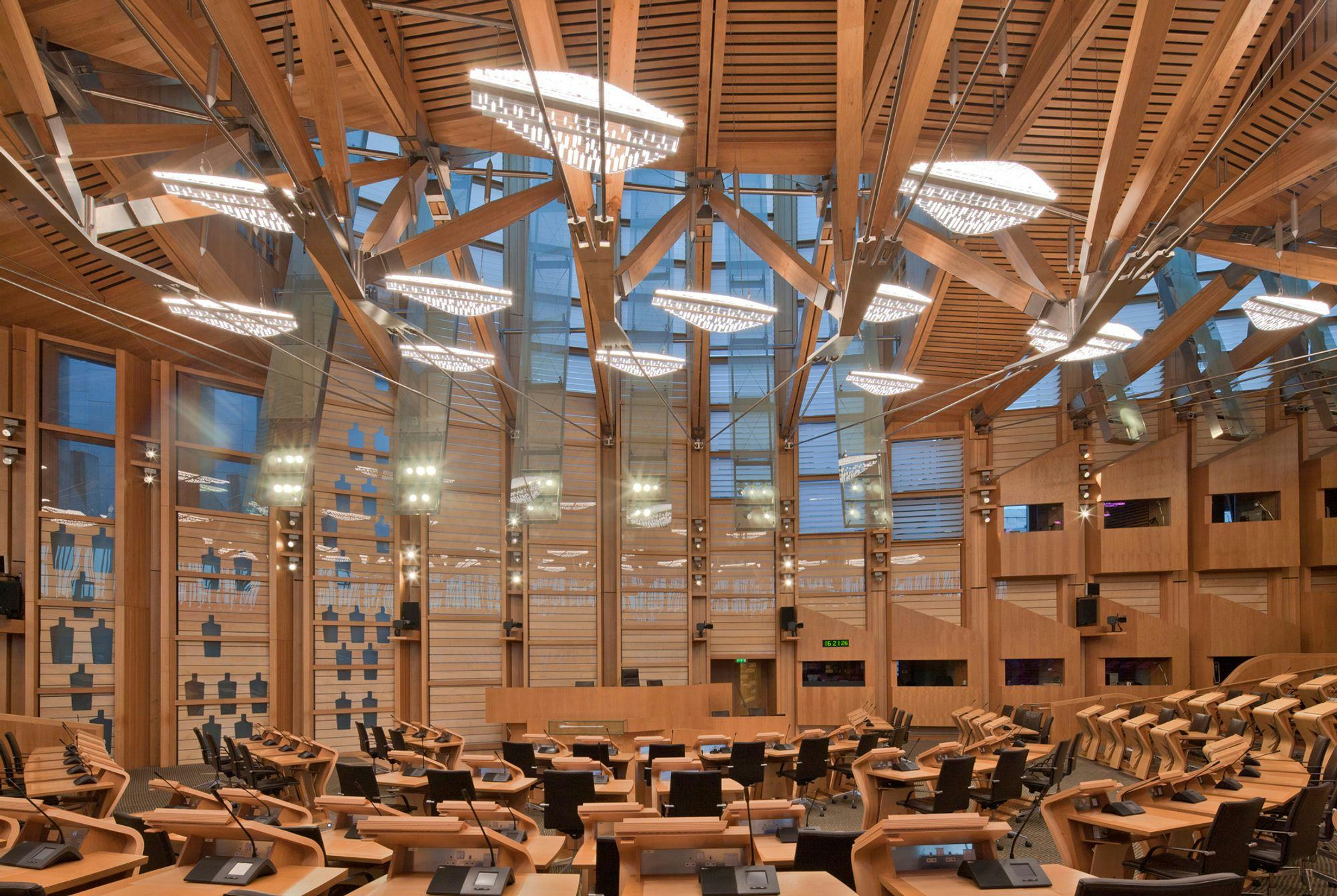 conference or concert hall made of wood, window frames on the walls and chandeliers in the ceiling that look like leaves or rain clouds